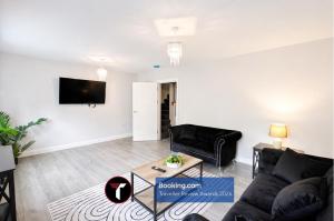 a living room with a couch and a tv on a wall at Spacious 4 Bedroom By Tara Stays Short Lets & Serviced Accommodation Aldershot With Free WiFi & Garden in Aldershot