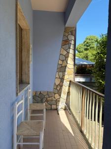 a balcony with two chairs and a stone wall at Mare & Pineta in Punta Marina +6 photos