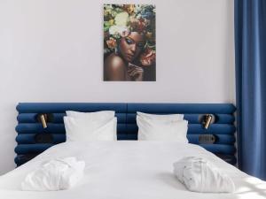a bed with a blue headboard and a picture of a woman at TRIBE Riga City Centre - Renovated 2026 in Riga +213 photos
