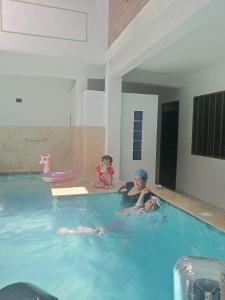 three children are playing in a swimming pool at Nirvana , Casa de Huéspedes in Melgar