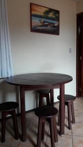 una mesa de madera con cuatro taburetes alrededor en Apart Hotel Praia do Pero, en Cabo Frío
