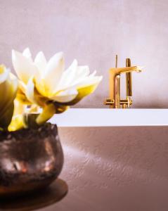 a yellow flower in a vase next to a brass faucet at Hotel Heureka in Venice