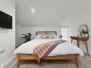 a bedroom with a large bed with a tv on the wall at Damson Barn in Bluntisham