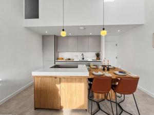 a kitchen with a wooden island with three chairs at Damson Barn in Bluntisham