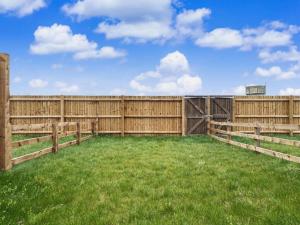 a wooden fence with green grass in a field at Damson Barn in Bluntisham