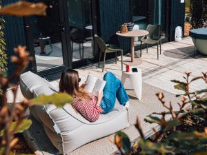 a woman laying on a couch reading a book at Luxe Tiny Suite met privé tuinbad in Meerssen