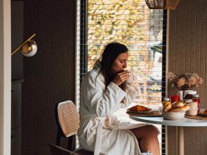 a woman sitting at a table eating food at Luxe Tiny Suite met privé tuinbad in Meerssen
