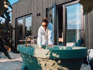 a woman standing in a bath tub in a house at Luxe Tiny Suite met privé tuinbad in Meerssen +7 photos