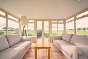 a living room with couches and a table and windows at Host & Stay - Cheviot View in Seahouses