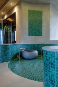 a bath tub in a bathroom with green tiles at Hotel Asteria in Venray