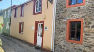 a building with red windows and a door on a street at Casa Lameiro in Cedeira