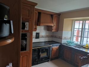 a kitchen with wooden cabinets and black appliances at Casa Lameiro in Cedeira