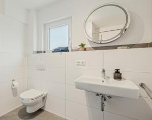 a white bathroom with a toilet and a mirror at Apartment am Fuchseck in Schorndorf