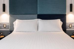 a large bed with white pillows and a blue headboard at Hotiday Napoli Maradona in Naples