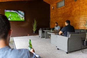 two men sitting at tables watching a soccer game on a tv at Complex Turistic Suatu in Suatul