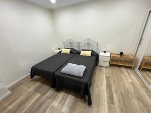 a bedroom with a black bed and a wooden floor at O Prior - Aposentos in Urzelina