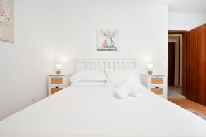 a white bedroom with a large white bed with white pillows at Apartment & Rooms Meri Tučepi in Tučepi