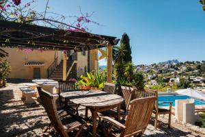 a patio with a table and chairs and a swimming pool at Robis Moraira in Benissa
