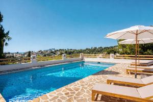 a swimming pool with two chairs and an umbrella at Robis Moraira in Benissa
