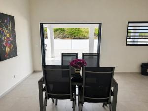 a dining room table with black chairs and a vase of flowers at Casa Trankilo in Fontein