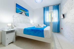 a white bedroom with a bed with blue curtains at Baia Verde - Sea Rooms in Baia Verde +36 photos
