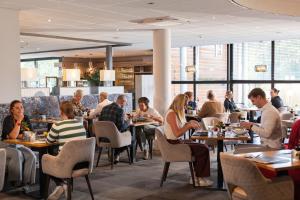 a group of people sitting at tables in a restaurant at Hotel Asteria in Venray