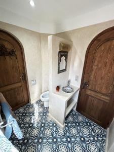 a bathroom with a toilet and a sink and two doors at Riad D’AR GANne by Carole in Essaouira