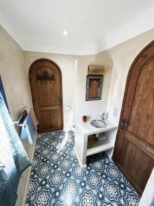 a bathroom with a sink and a wooden door at Riad D’AR GANne by Carole in Essaouira