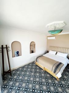 a bedroom with a bed and a blue and white carpet at Riad D’AR GANne by Carole in Essaouira