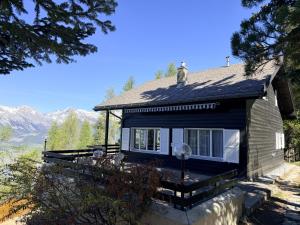 a small black house with mountains in the background at Cache-Cache MOUNTAIN & QUIET chalet 10 pers in Veysonnaz