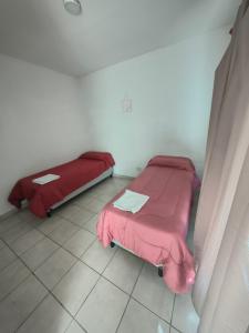 two beds in a room with pink sheets at Depto Civora 4 in Villa Regina