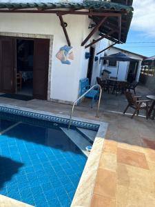 a swimming pool in front of a house at Pousada Casa do Telhado Verde in Cabo Frio