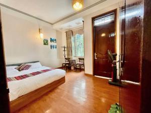 a bedroom with a bed and a table and a door at Su Ha Giang Hostel in Ha Giang