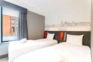 two beds in a room with a window at easyHotel Oxford in Oxford