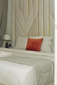 a white bed with a red pillow on it at Top city Homes in Lagos