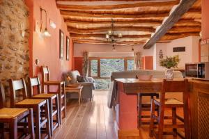 a kitchen and living room with wooden ceilings and a bar at Casa Alfurán in Alfornón