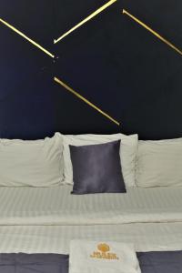 a bed with white pillows and a black wall at Top city Homes in Lagos