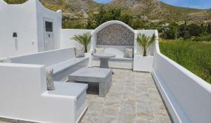 a patio with white furniture and a table and benches at Papafotis Apartments & Suites in Alinda