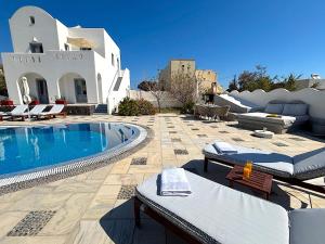 a swimming pool with lounge chairs and a house at Villa Thea in Kamari