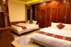 a bedroom with two beds and wooden cabinets at Su Ha Giang Hostel in Ha Giang