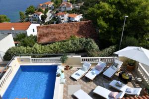 a villa with a swimming pool and lawn chairs at House Postira Horizon in Postira