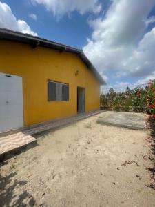 a yellow house with a field of flowers at Casa aconchegante em Bezerros- REI DAVID CONDOMÍNIO CLUBE in Bezerros