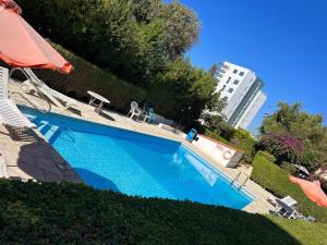 a blue swimming pool with an umbrella and a building at Central 2 Bedroom Apartment Pafia 2 in Paphos