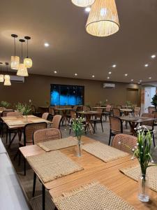 a restaurant with wooden tables and chairs and lights at Hotel do Carmo in Piracuruca