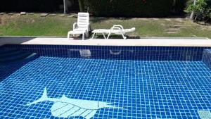 a swimming pool with two chairs and a table at bungalow with swimming pool in Rawai Beach +3 photos