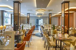 a restaurant with tables and chairs and a chandelier at Wellness- und Gartenhotel Heusser in Bad Dürkheim