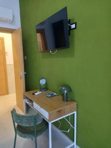 a room with a desk and a tv on a green wall at Glamonia rooms in Campobasso
