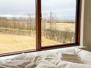 a bed in front of a window looking out at a field at Fagrahlid Guesthouse in Hvolsvöllur