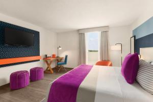 a hotel room with a bed, table, chairs and a television at TRYP by Wyndham Isla Verde in San Juan