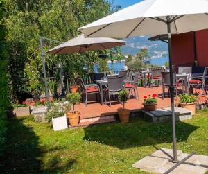 a patio with tables and chairs and an umbrella at Villa Leilani B&B in Sale Marasino